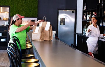 Delivery person picking up takeout bags at restaurant